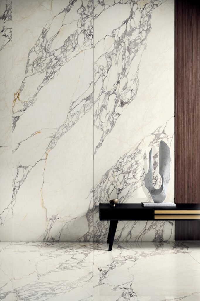 Luxury interior with large white marble paneling featuring bold gray veins. A modern black console with a sculpture and decor adds elegance.