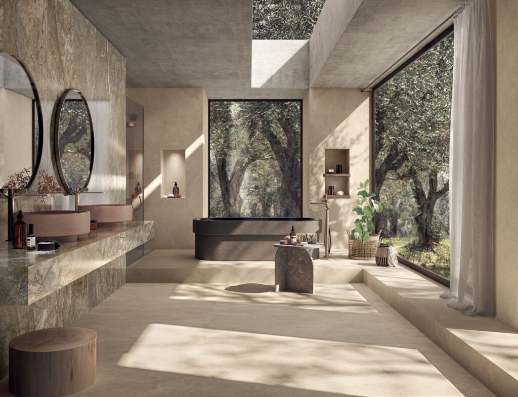 Luxurious bathroom with large windows showcasing a forest view. Features a black tub, stone vanity with round mirrors, and plants, creating a serene atmosphere.