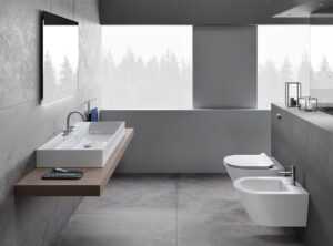 Modern grey stone-look bathroom featuring a large rectangular white ceramic basin on a wooden shelf next to a wall-hung toilet and bidet.
