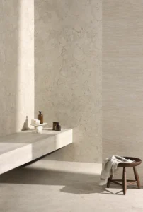 Minimalist bathroom space featuring large-format beige stone-look wall tiles alongside a fluted accent wall from the Portobello Aeterna X Avorio collection.