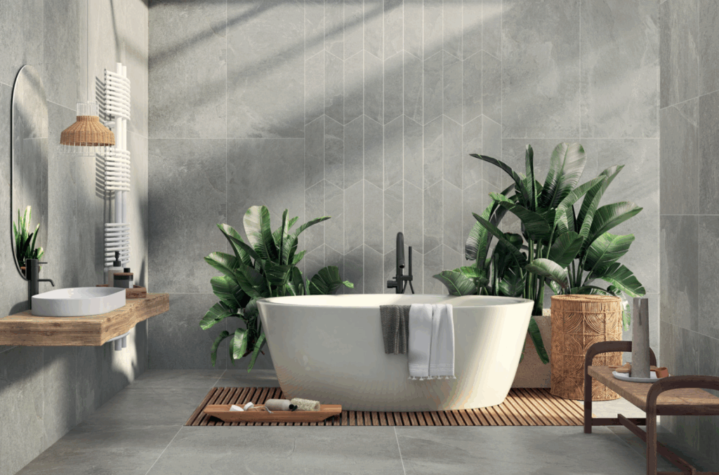 Modern bathroom with a sleek bathtub surrounded by lush green plants. Gray textured walls, wooden accents, and soft lighting create a tranquil spa-like ambiance.