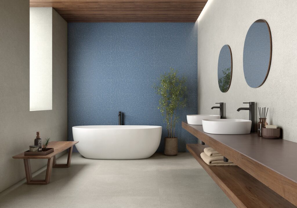 Modern bathroom with a freestanding white tub, blue accent wall, wood ceiling, and floating vanity. Two round mirrors, potted plant, and minimalist decor.