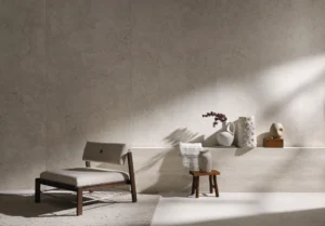 Elegant lounge area featuring large-format stone-look wall tiles from the Portobello Aeterna X Bianco collection, paired with minimalist decorative ceramic vases.
